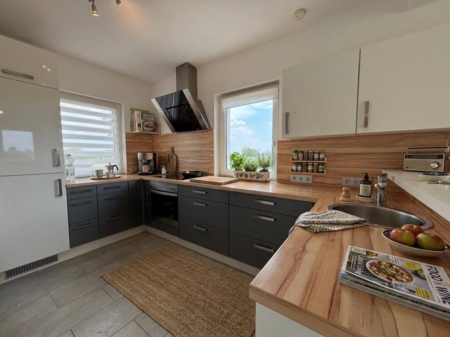 Geräumige Küche mit integriertem Kühlschrank, Spüle und viel Arbeitsfläche, mit Blick ins Grüne.