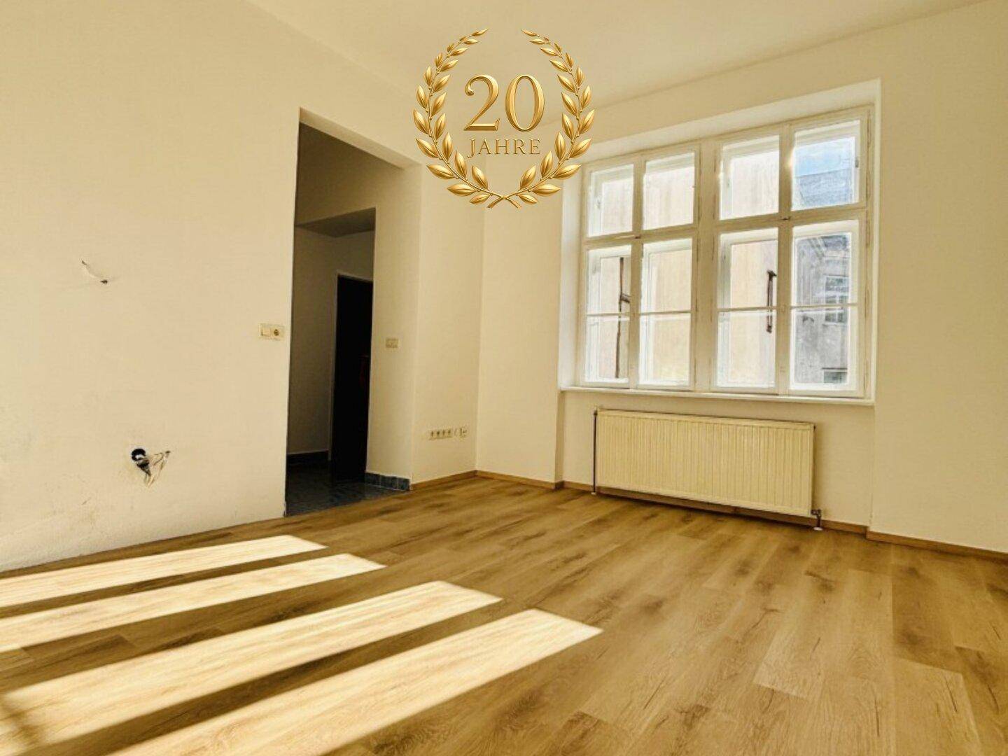 Heller Raum mit großen Fenstern und neuem Laminatboden, ideal als Wohn- oder Schlafzimmer nutzbar.