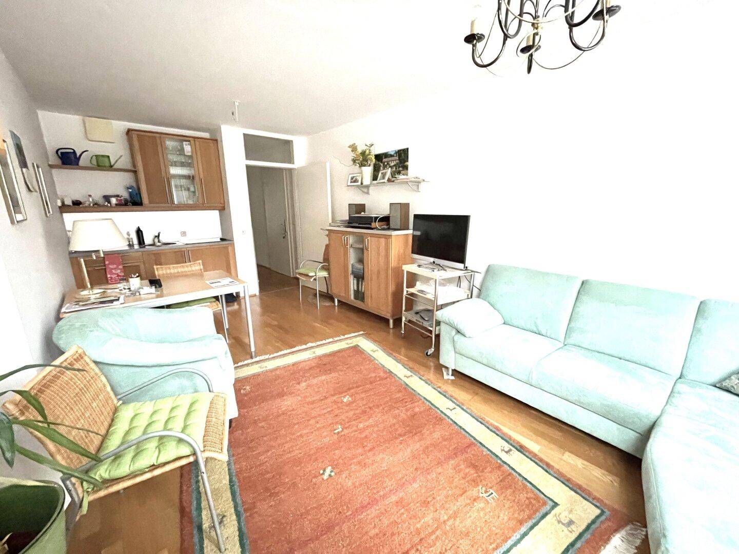 Gemütliches Wohnzimmer mit Sofa, Teppich und Holzboden, offen gestaltet.