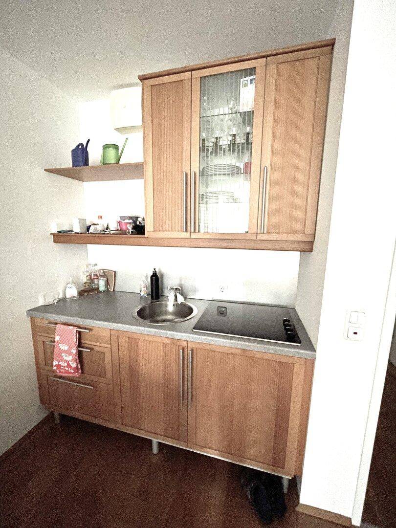 Kompakte Küchenzeile mit Holzschränken, Spüle und integriertem Kochfeld.