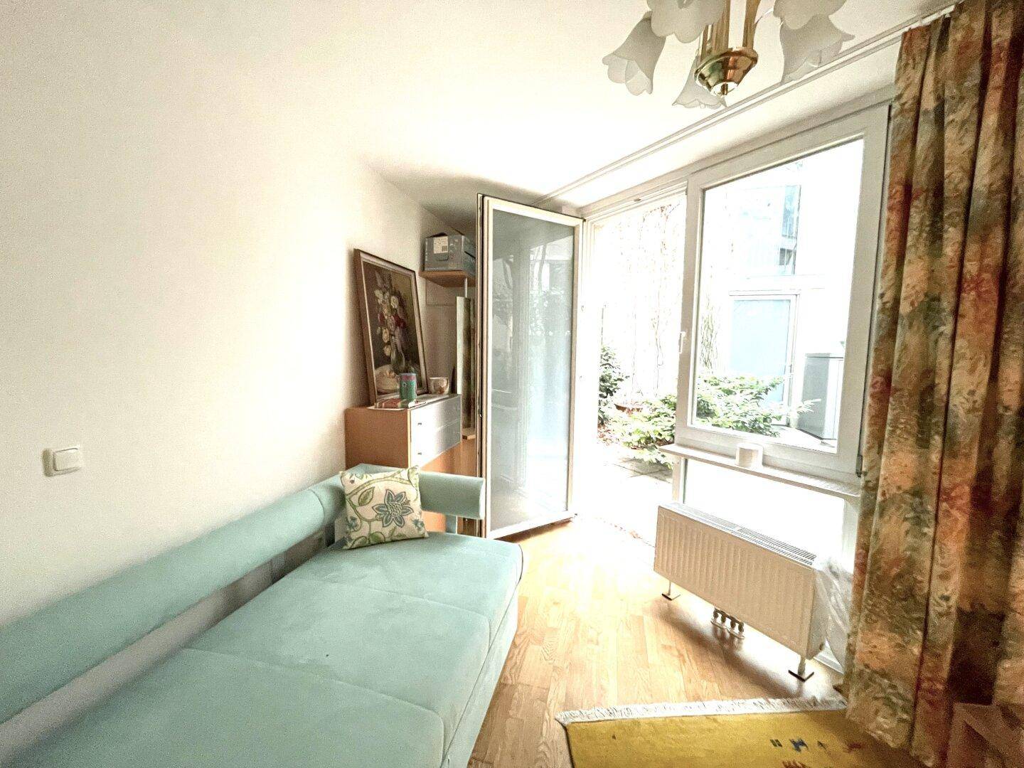 Heller Raum mit Schlafsofa und Zugang zu einem Außenbereich durch große Fenster.