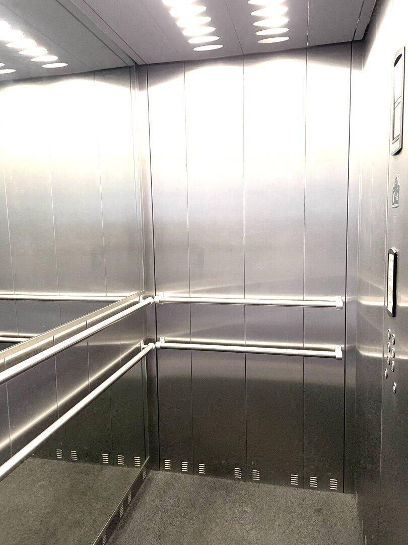Moderner Aufzug mit Edelstahlwänden und Spiegeln im Innenraum.