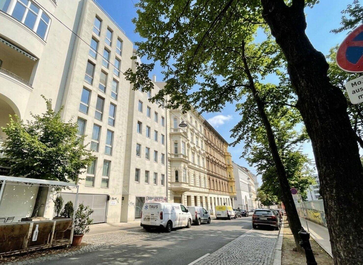 Straßenansicht mit moderner Architektur und traditionellen Gebäuden unter blauem Himmel.