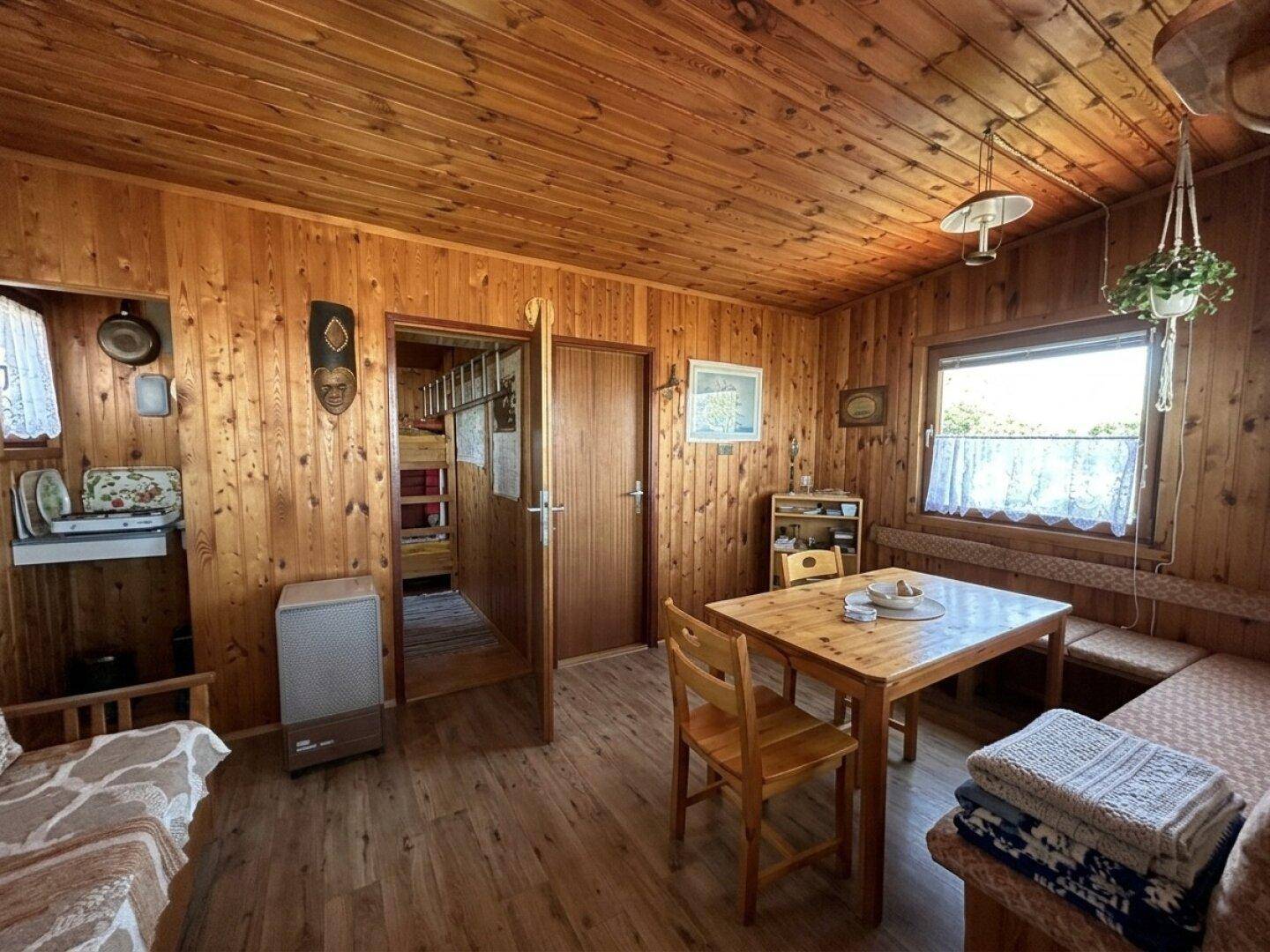 Kombinierter Wohn- und Essbereich mit holzvertäfelten Wänden, Esstisch und gemütlichem Sofa.