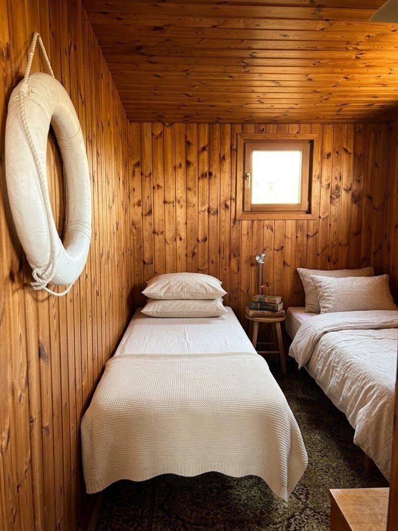 Kleines Schlafzimmer mit zwei Einzelbetten und holzvertäfelten Wänden, dekoriert mit einem Rettungsring.