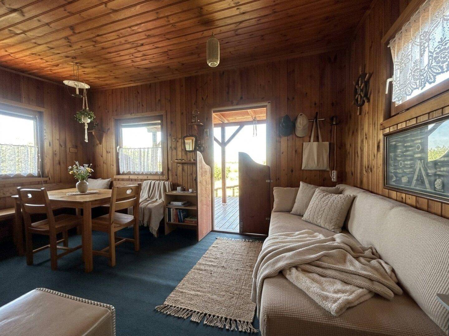 Gemütlicher Wohnbereich mit Sofa, Esstisch und Blick auf die Natur durch die Fenster.
