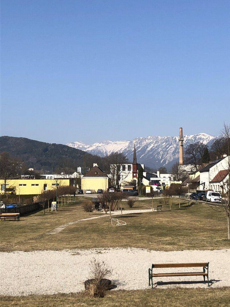 Weitläufige Außenansicht mit Bergen im Hintergrund und einem sonnigen Parkbereich.