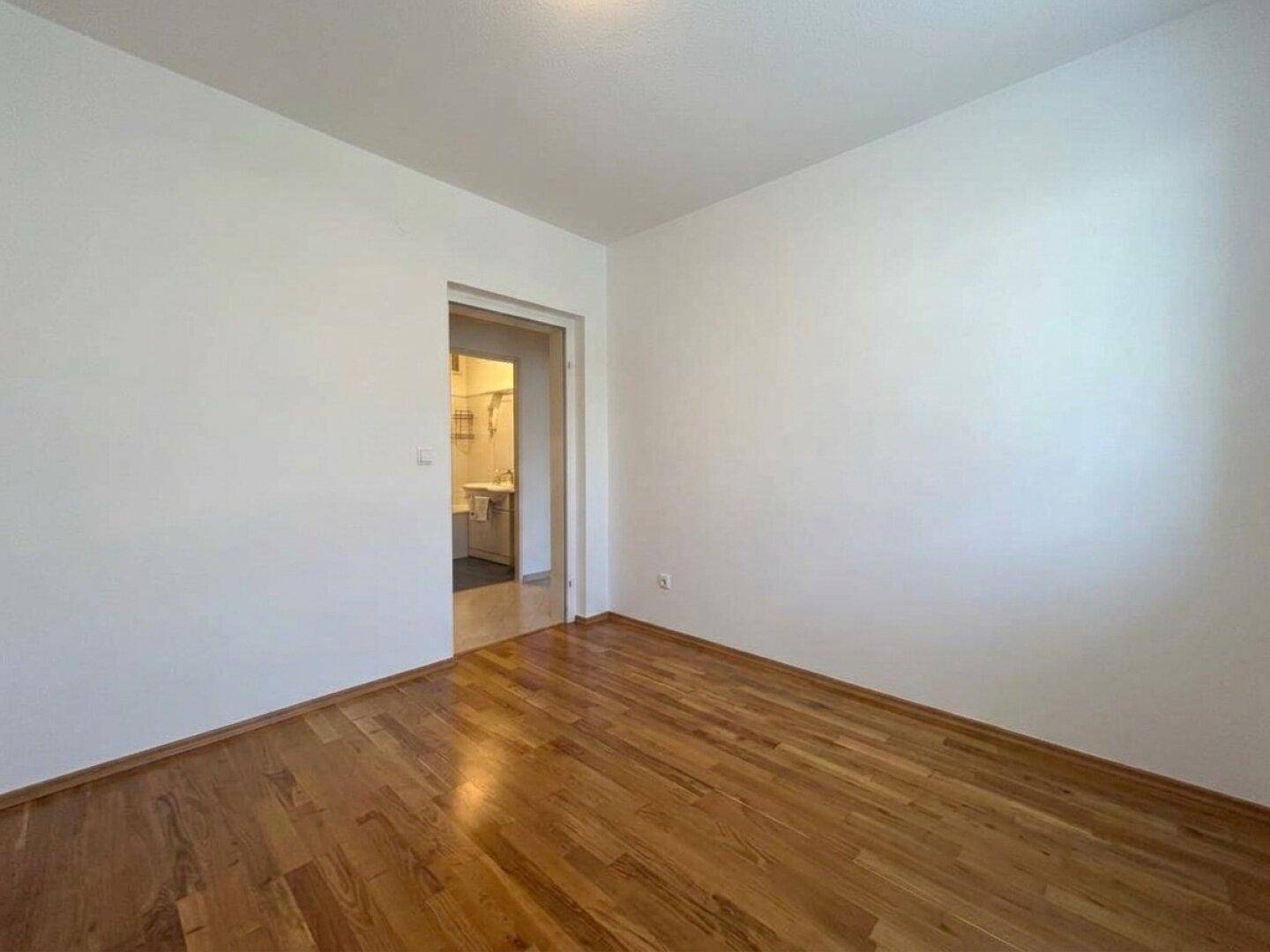 Schlafzimmer mit Parkettboden und direktem Zugang zu einem Badezimmer.