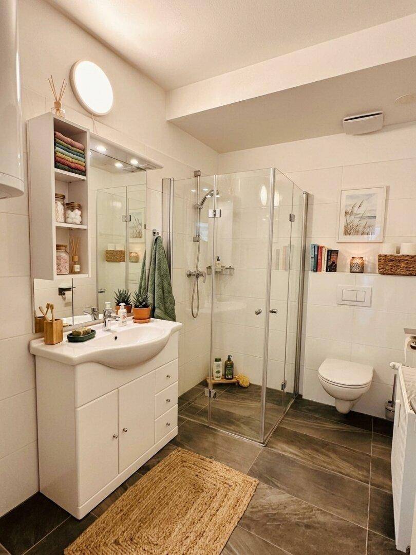 Modernes Badezimmer mit Duschkabine, Waschtisch und Wand-WC.