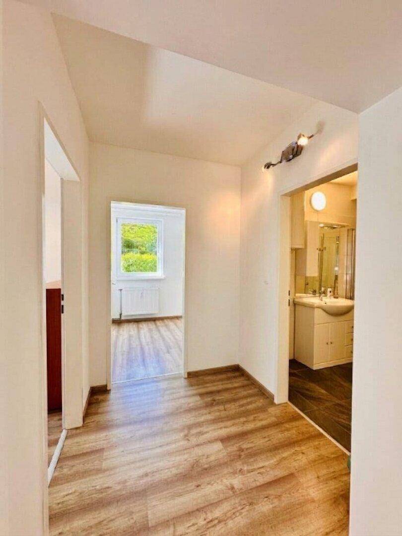 Heller Flur mit Laminatboden, der zu weiteren Zimmern und dem Badezimmer führt.