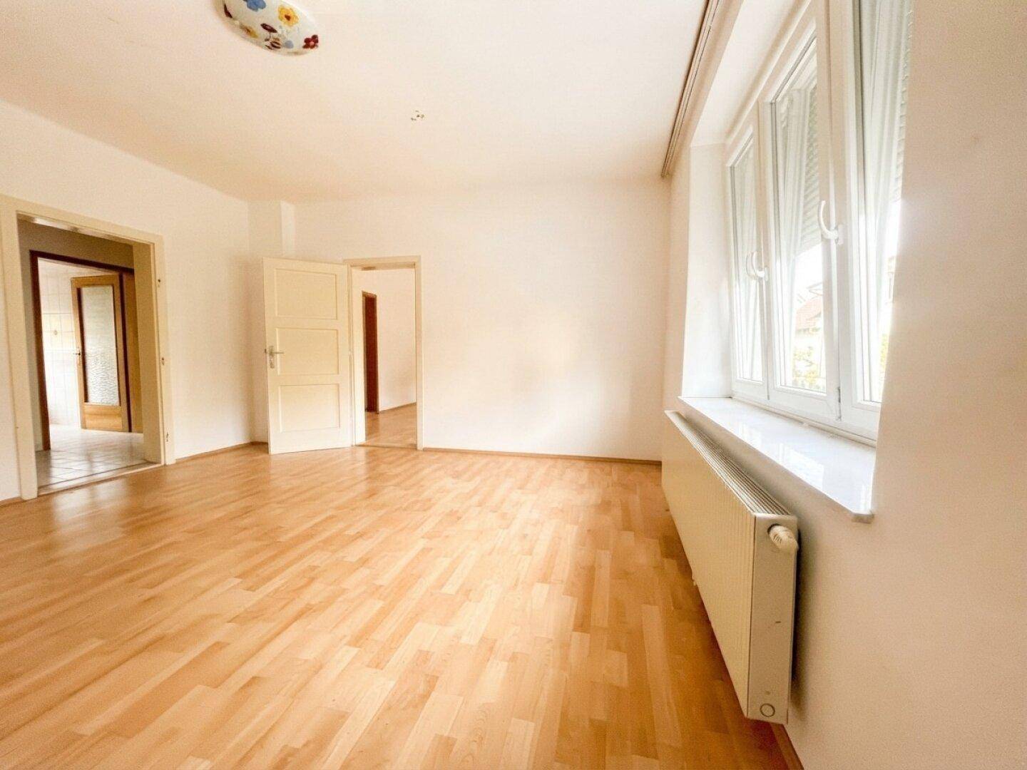 Helles Zimmer mit Laminatboden und mehreren Türen, die zu anderen Räumen führen.