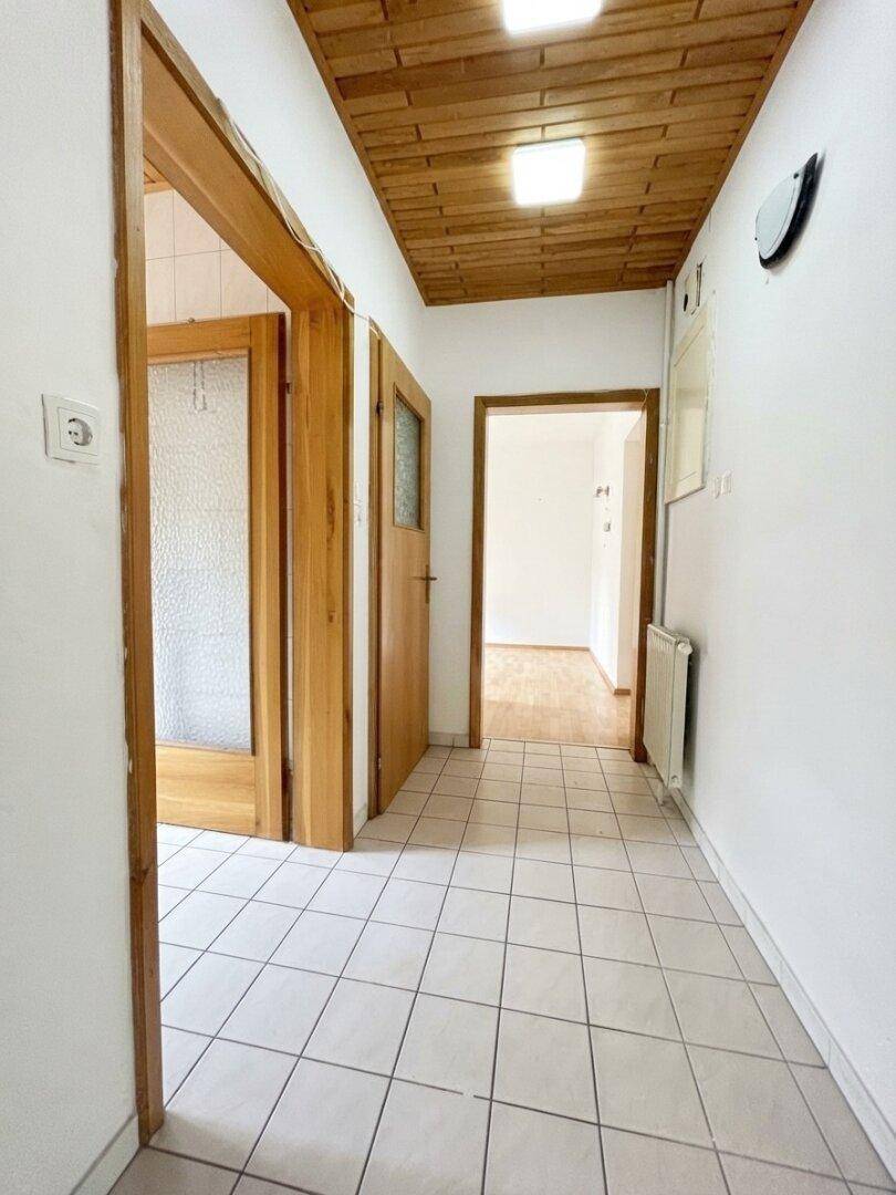 Flur mit Fliesenboden und einer Holzdecke, der zu weiteren Räumen führt.