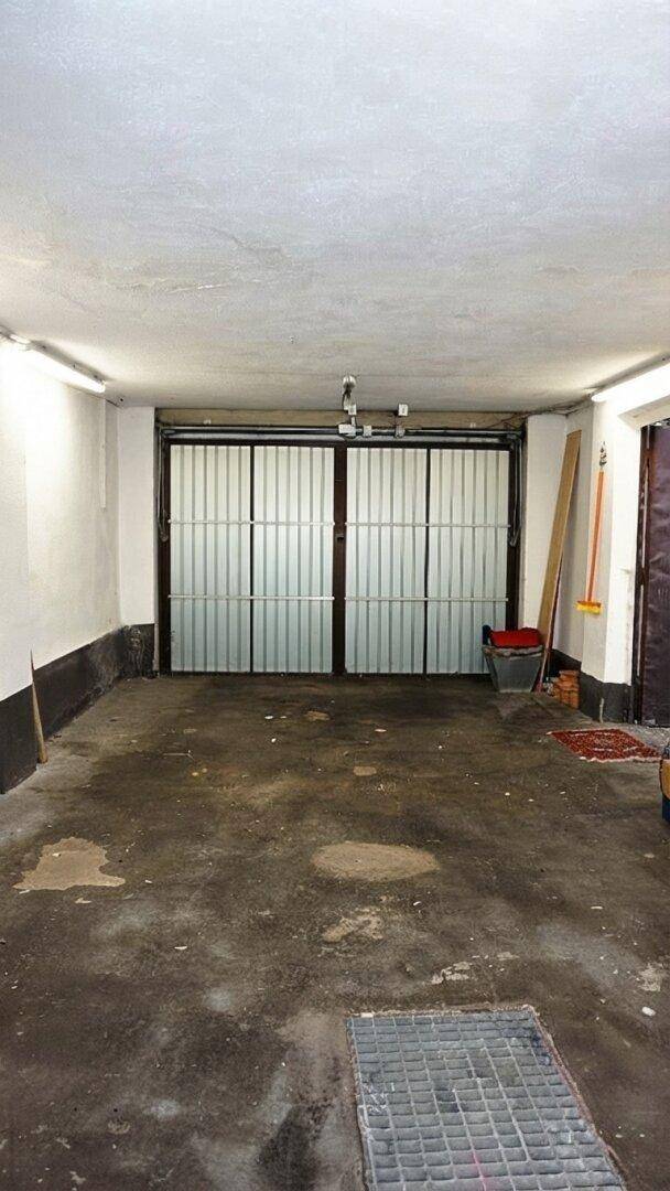 Geräumige Garage mit Rolltor und Betonboden, bietet Platz für ein Fahrzeug.