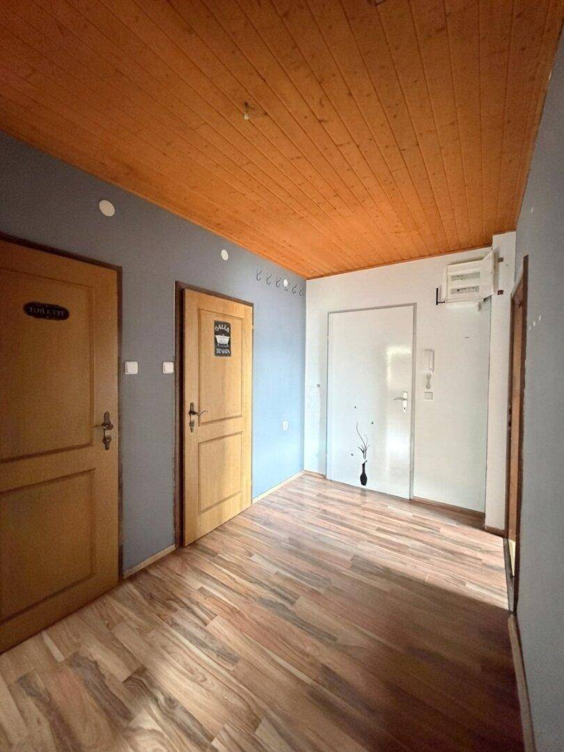 Geräumiger Flur mit Holzbalkendecke und Laminatboden, der zu verschiedenen Zimmern führt.