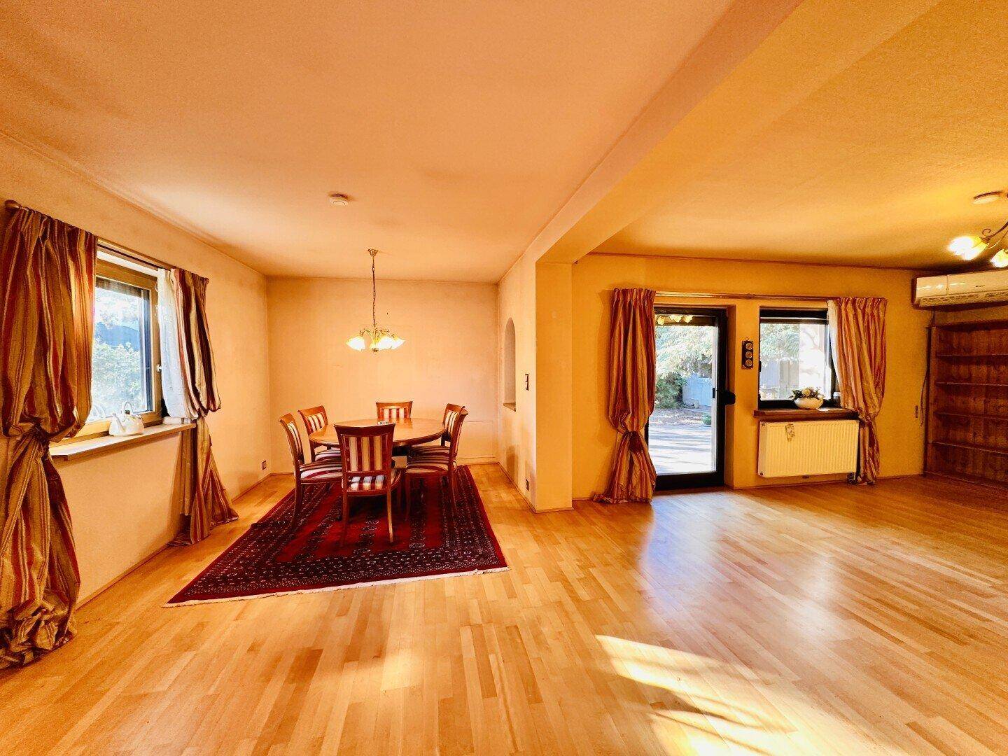 Essbereich mit Holzboden, rundem Esstisch und Blick in den Wohnbereich.