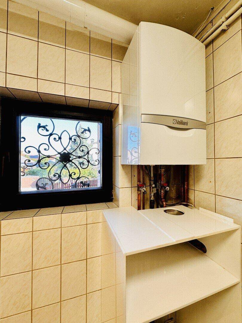 Kleiner Raum mit Heizungsanlage, gefliesten Wänden und Fenster.