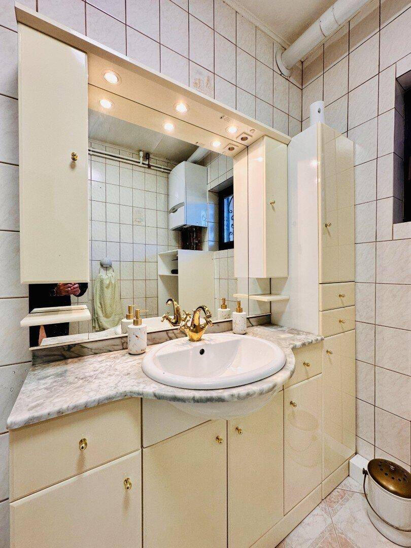 Waschtisch im Badezimmer mit Marmorplatte, Spiegel und integrierter Beleuchtung.