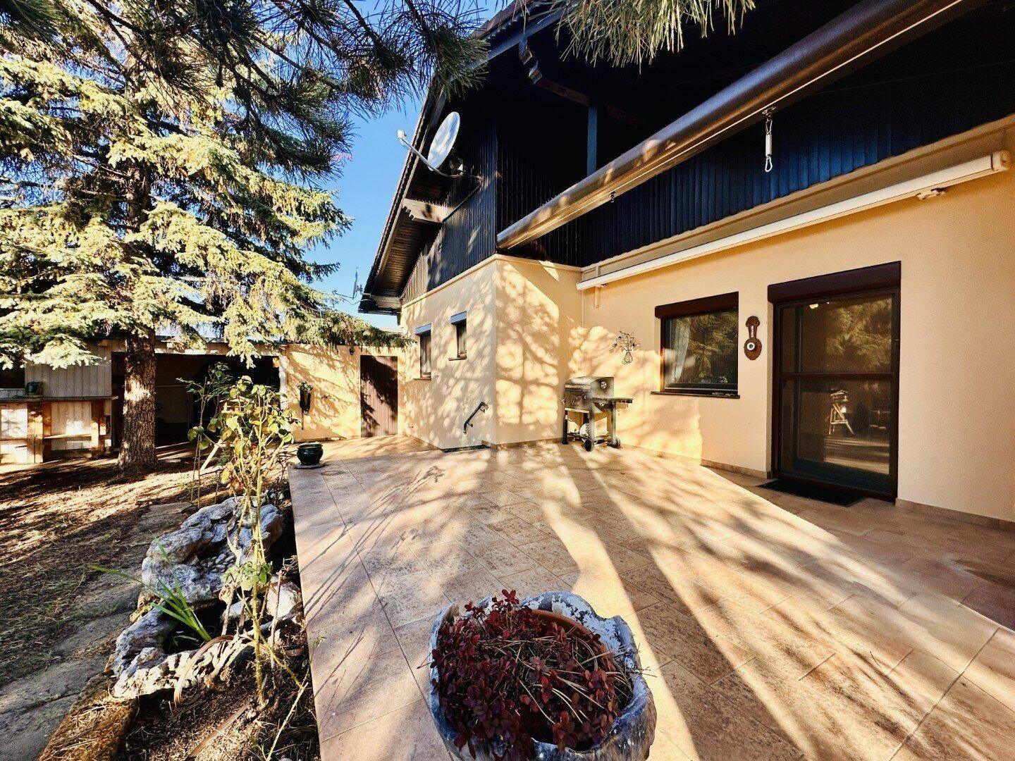 Große gepflasterte Terrasse an der Rückseite des Hauses mit viel Sonnenlicht.
