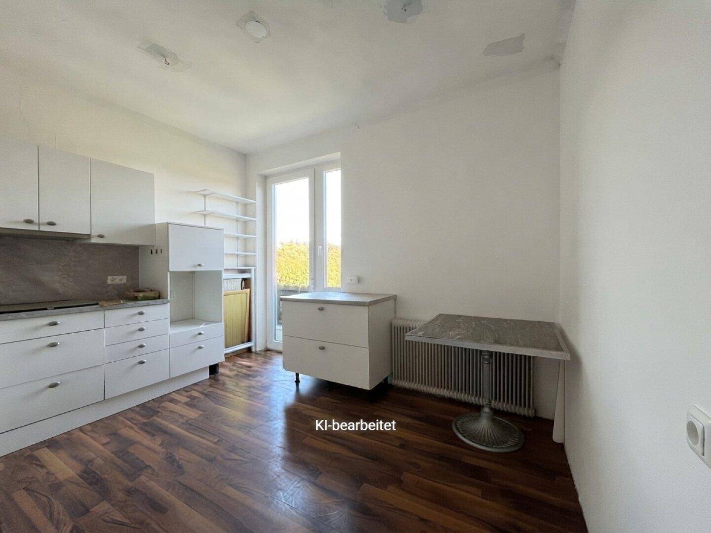Funktionale Küche mit weißen Schränken, Arbeitsplatte und Fenster mit Ausblick.