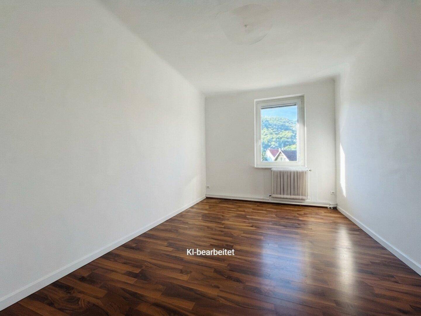 Kleineres Zimmer mit Laminatboden und einem Fenster, das viel Tageslicht hereinlässt.