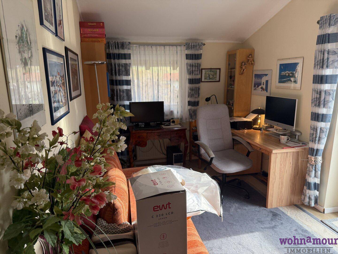 Funktionales Arbeitszimmer mit Schreibtisch, Bürostuhl und Blick ins Grüne.