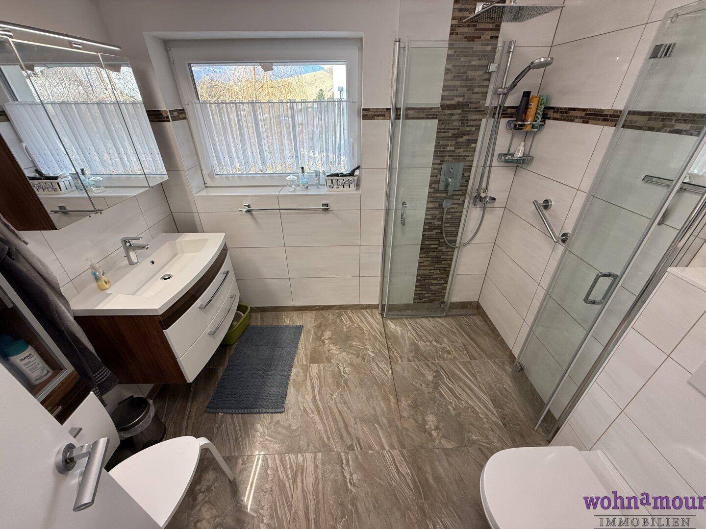 Modernes Badezimmer mit ebenerdiger Dusche, Waschbecken und Fenster für Tageslicht.