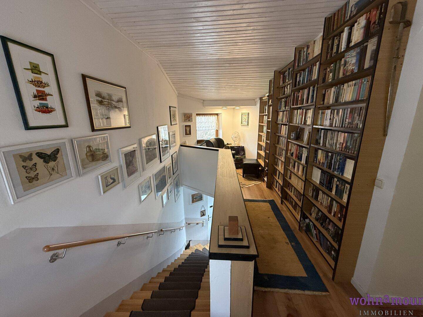 Treppenaufgang mit einer beeindruckenden Bücherwand, die eine gemütliche Leseatmosphäre schafft.