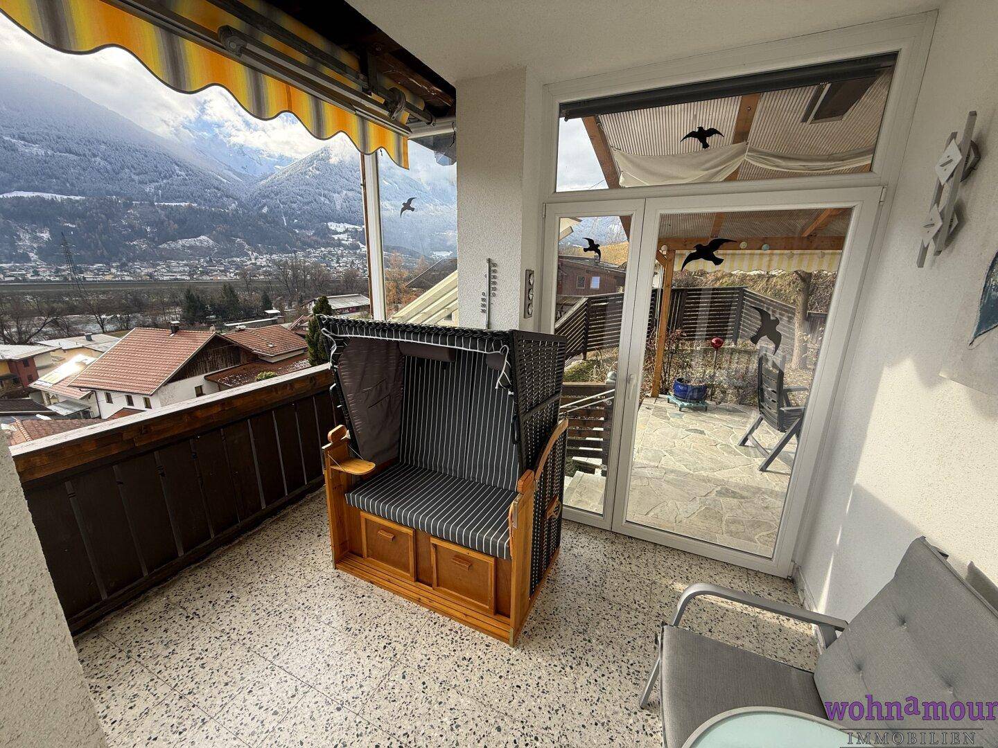 Sonniger Balkon mit Strandkorb und atemberaubendem Panoramablick auf die Berge.
