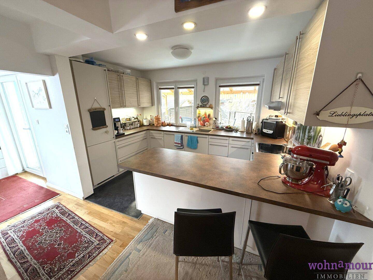 Moderne Küche mit U-förmiger Arbeitsplatte, Frühstücksbar und Blick nach draußen.
