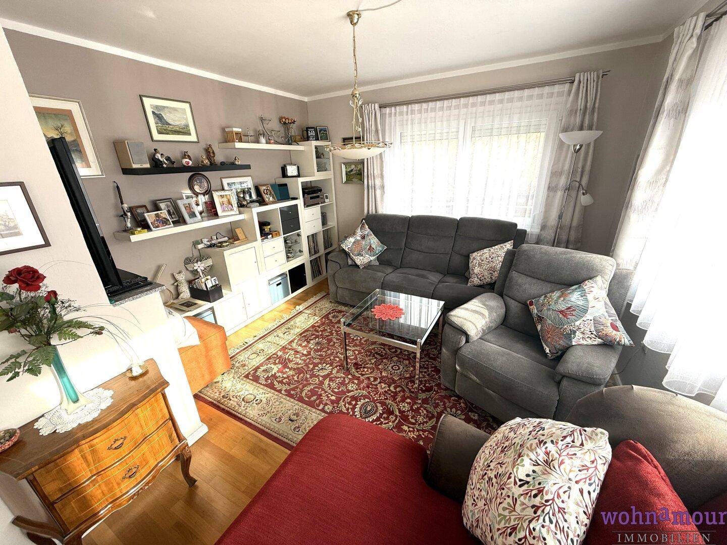 Gemütliches Wohnzimmer mit bequemen Sofas, Teppich und dekorativen Regalen.