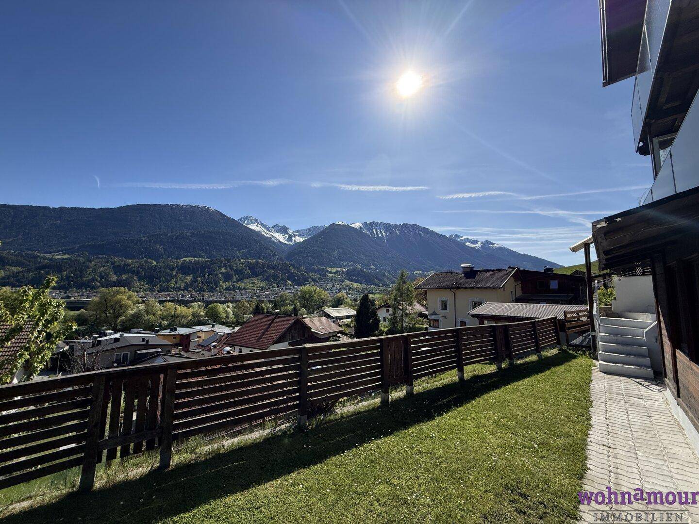 Sonnige Gartenseite des Hauses mit Blick auf die schneebedeckten Berge und die grüne Umgebung.