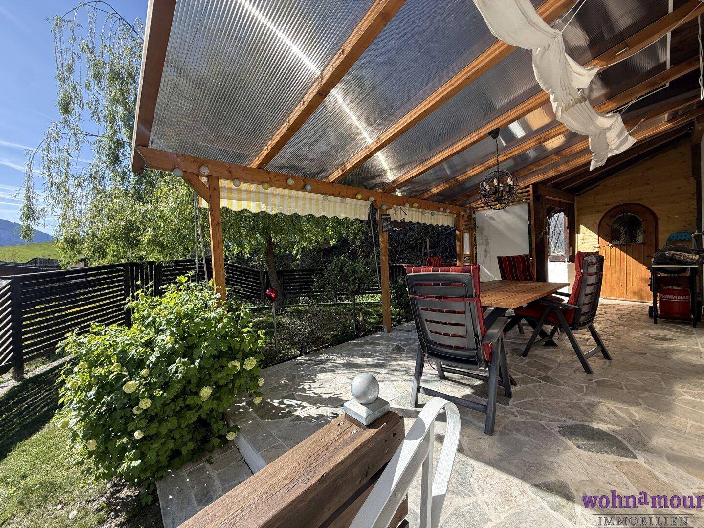 Gemütliche überdachte Terrasse mit Essbereich und Blick ins Grüne, ideal für Entspannung.