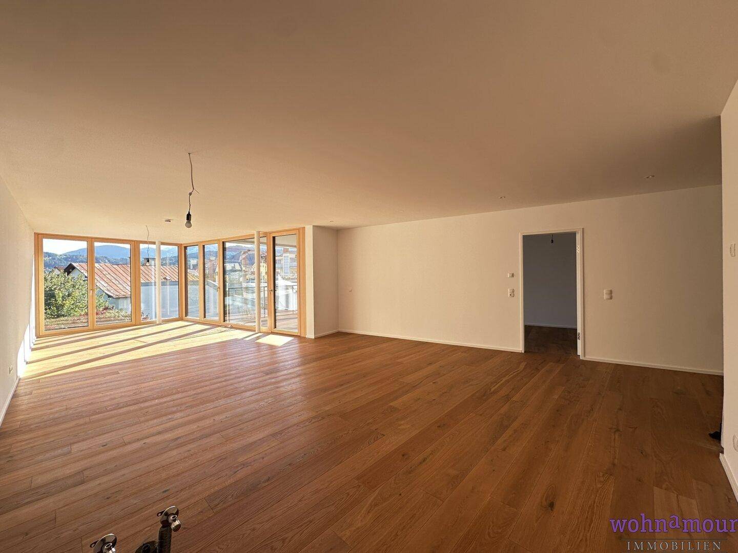 Geräumiger, heller Wohnbereich mit hochwertigem Parkettboden und großen Fensterfronten für viel Tageslicht.