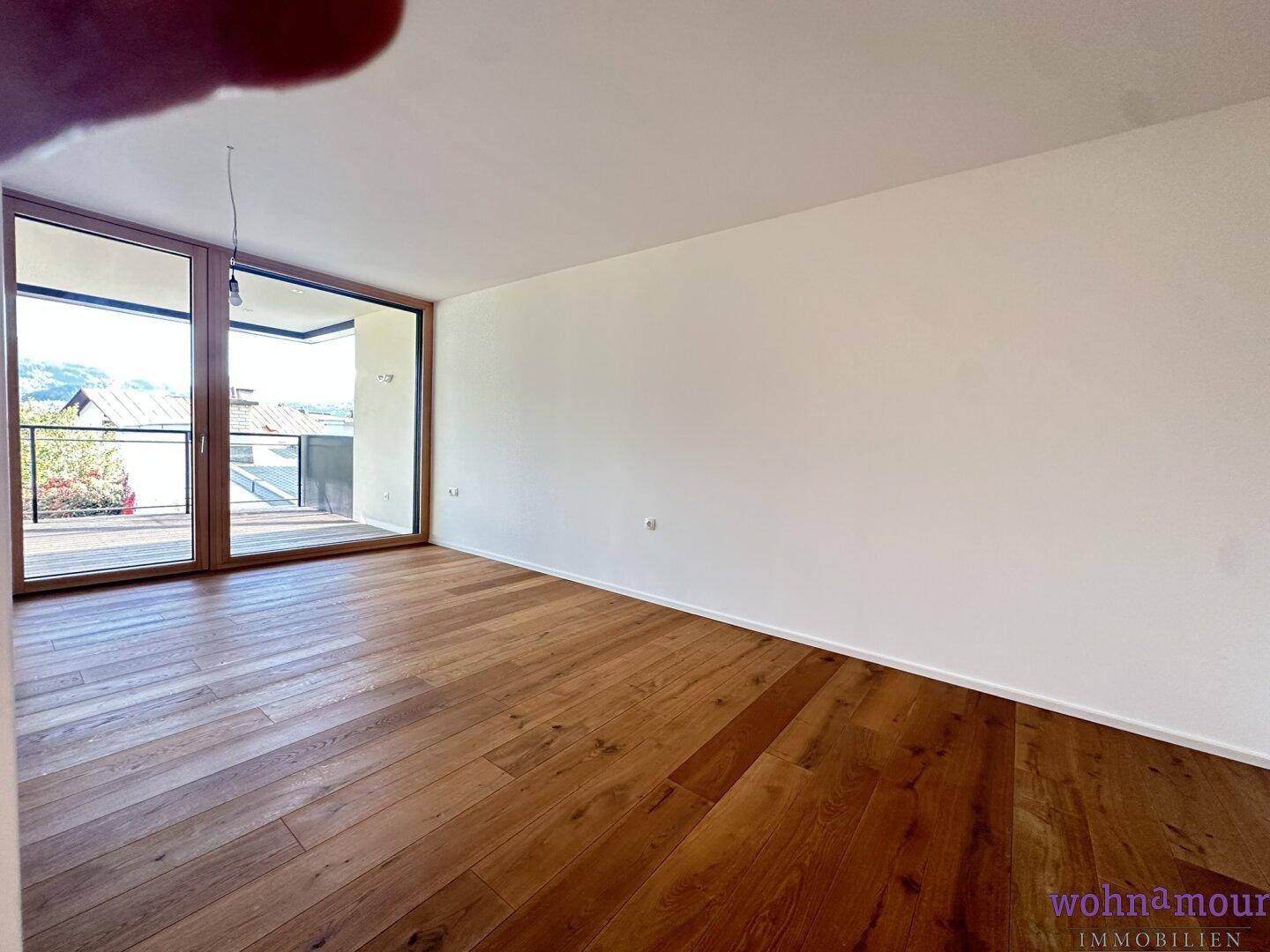 Heller Raum mit Holzboden und Zugang zu einem Balkon, ideal als Schlaf- oder Wohnzimmer nutzbar.
