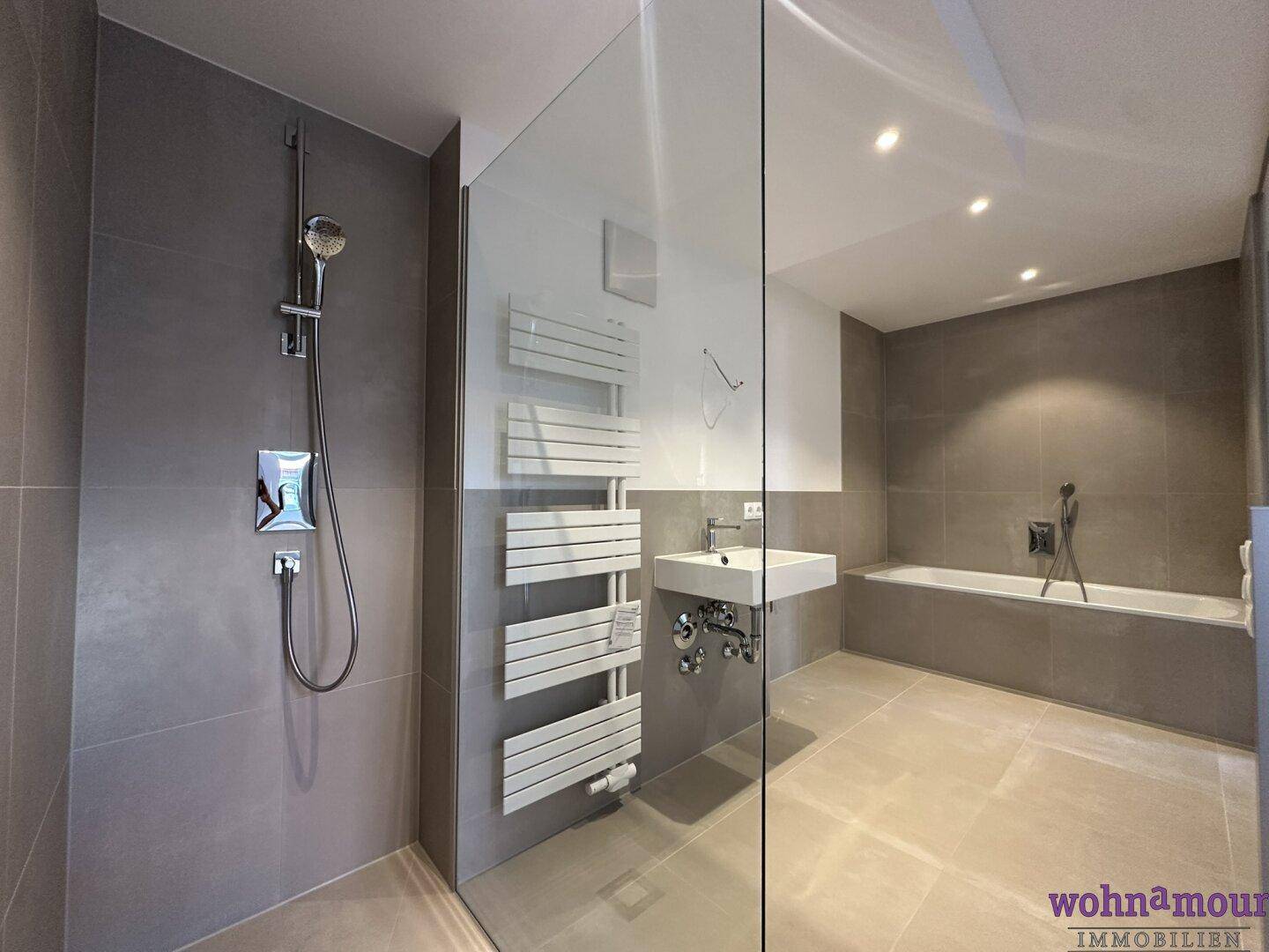 Modernes Badezimmer mit begehbarer Dusche, Badewanne, beheiztem Handtuchhalter und eleganten Fliesen.