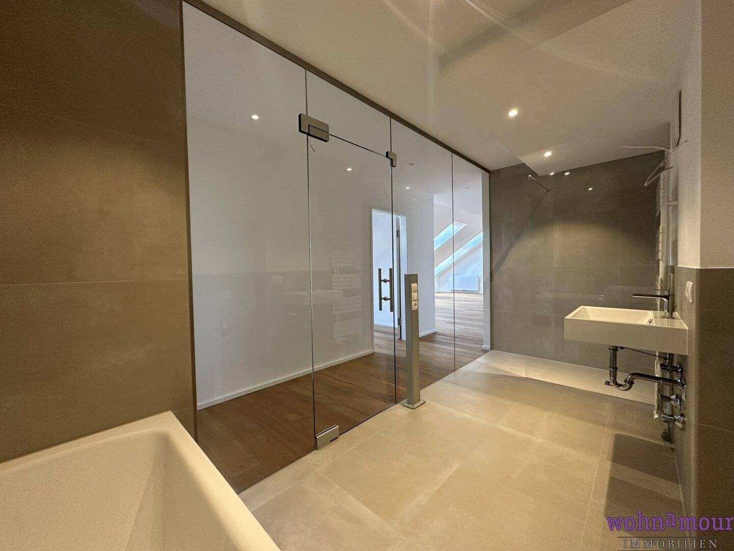 Geräumiges, modernes Badezimmer mit Glaswand zur angrenzenden Wohnfläche und hochwertigen Armaturen.