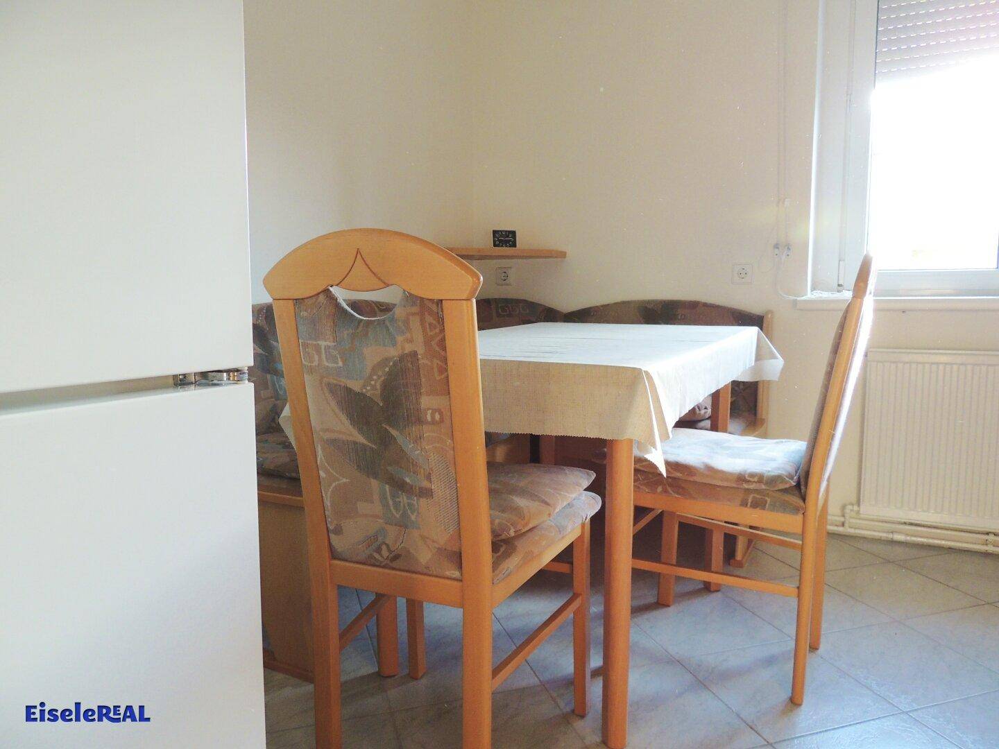 Gemütliche Essecke in der Küche mit Holztisch, Stühlen und Fenster für natürliches Licht.