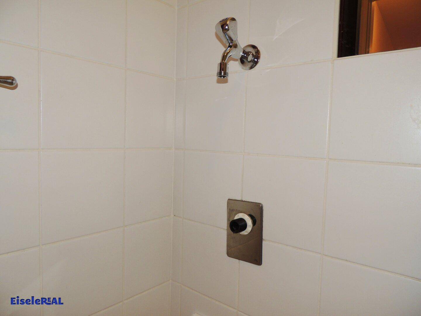 Wandbereich in einem Badezimmer mit weißen Fliesen und einem Wasserhahn.