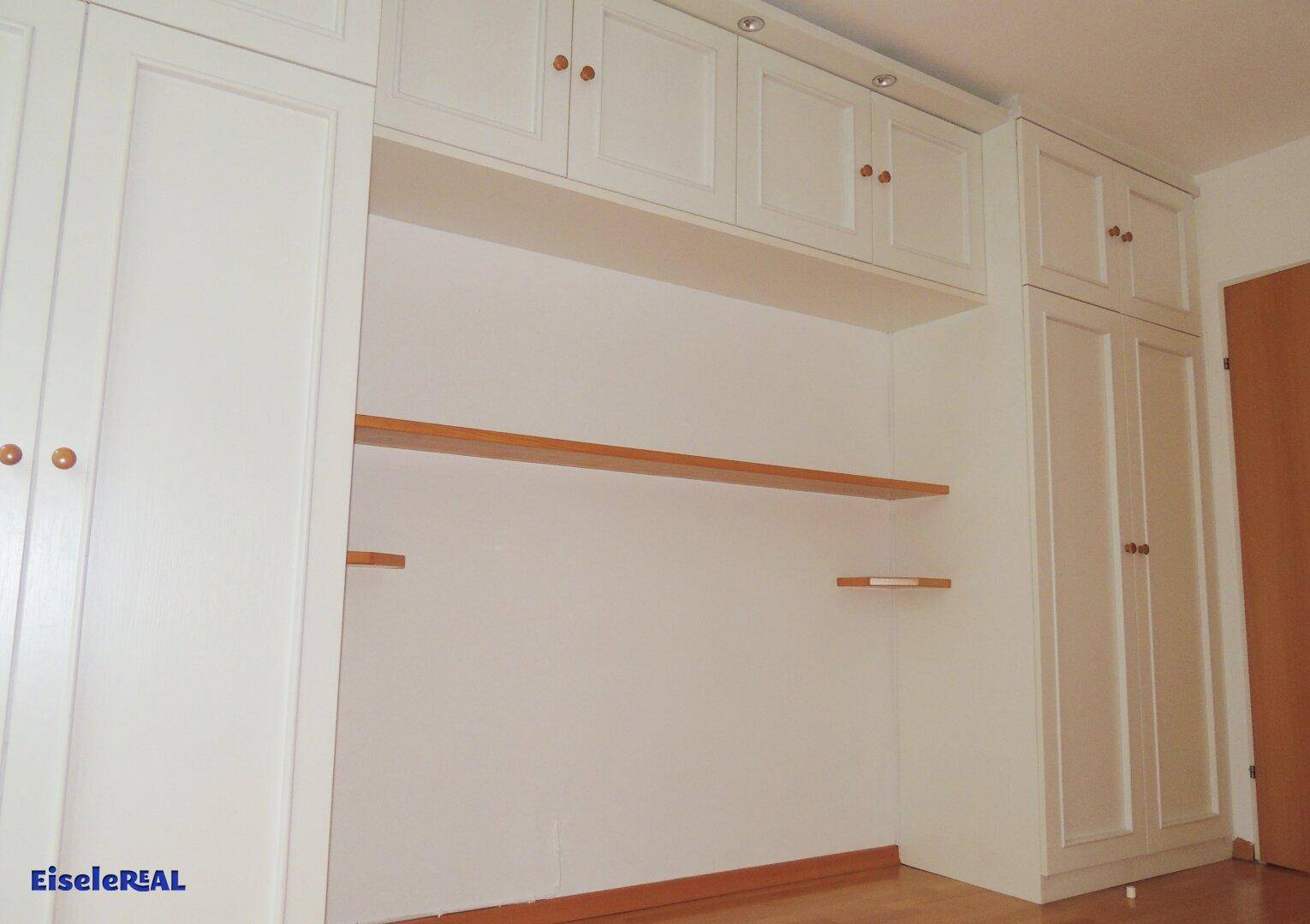 Detailansicht der weißen Einbauschränke und Regale in einem hellen Zimmer.