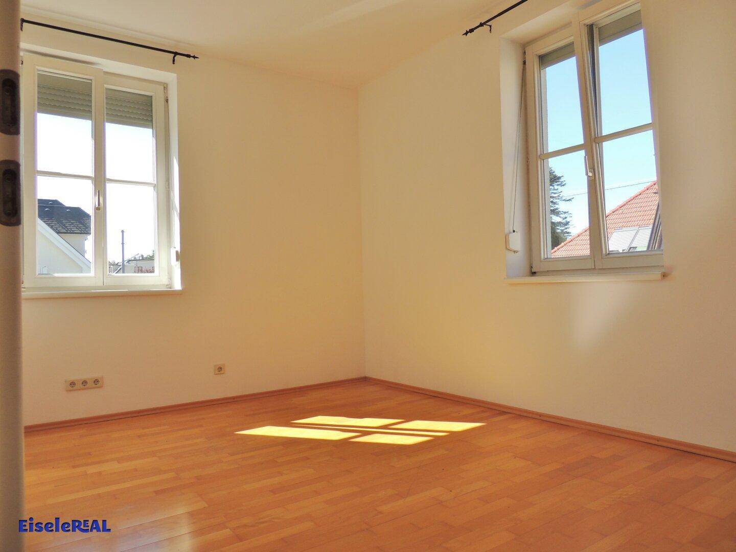 Helles Zimmer mit Parkettboden und zwei Fenstern, ideal als Schlaf- oder Arbeitszimmer.