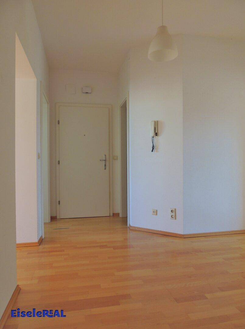 Heller Flur mit Parkettboden und Gegensprechanlage, der zu weiteren Räumen führt.
