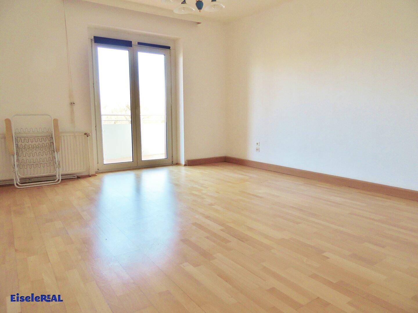 Helles Zimmer mit Parkettboden und direktem Zugang zu einem Balkon, ideal für Schlaf- oder Wohnbereich.