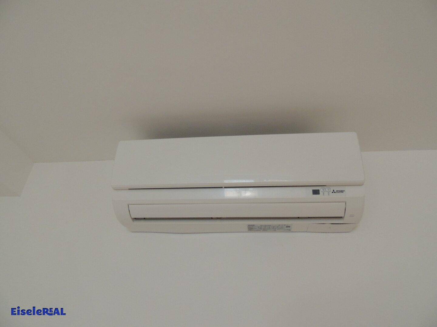 Eine weiße Klimaanlage ist an einer hellen Wand montiert, bereit für den Einsatz und in gutem Zustand.