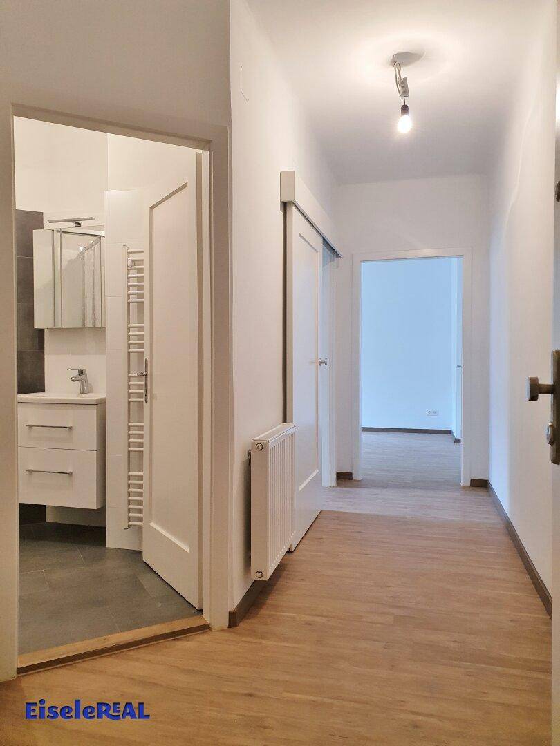 Heller Flur mit Holzfußboden und Türen zu angrenzenden Zimmern, inklusive Badezimmer.