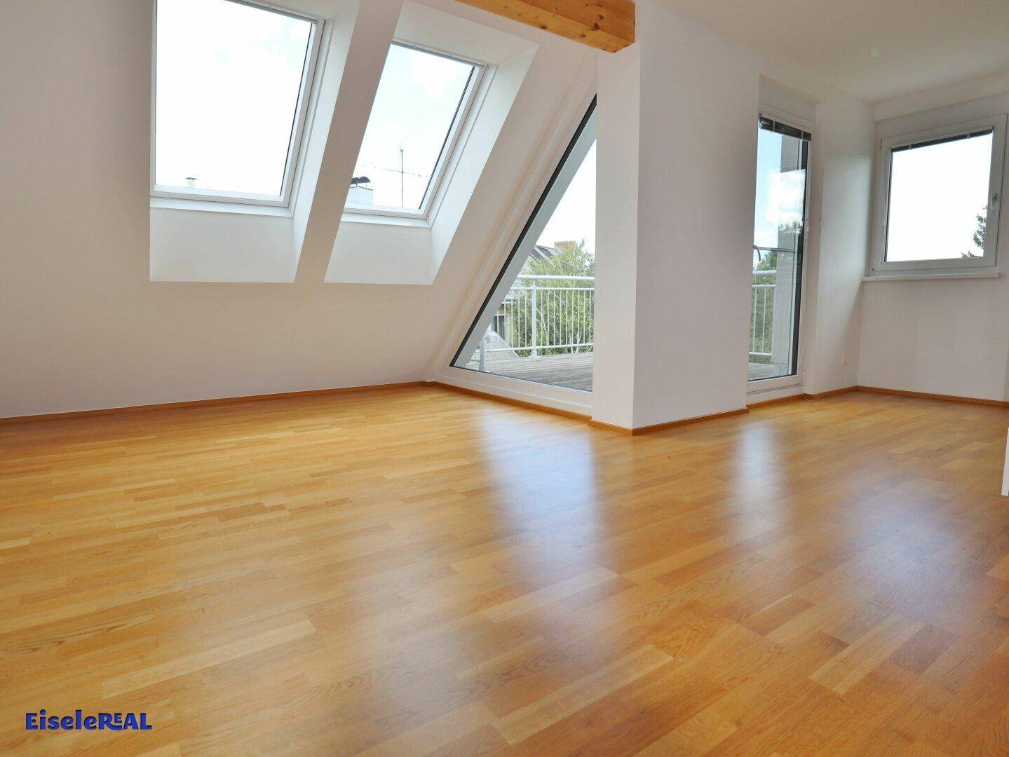 Lichtdurchfluteter Wohnraum mit Parkettboden, Dachfenstern und Zugang zum Außenbereich.