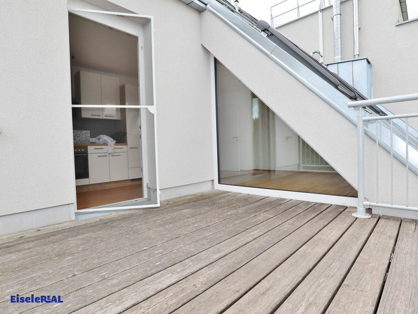 Balkon mit Holzboden und direktem Zugang zum Innenbereich der Wohnung.