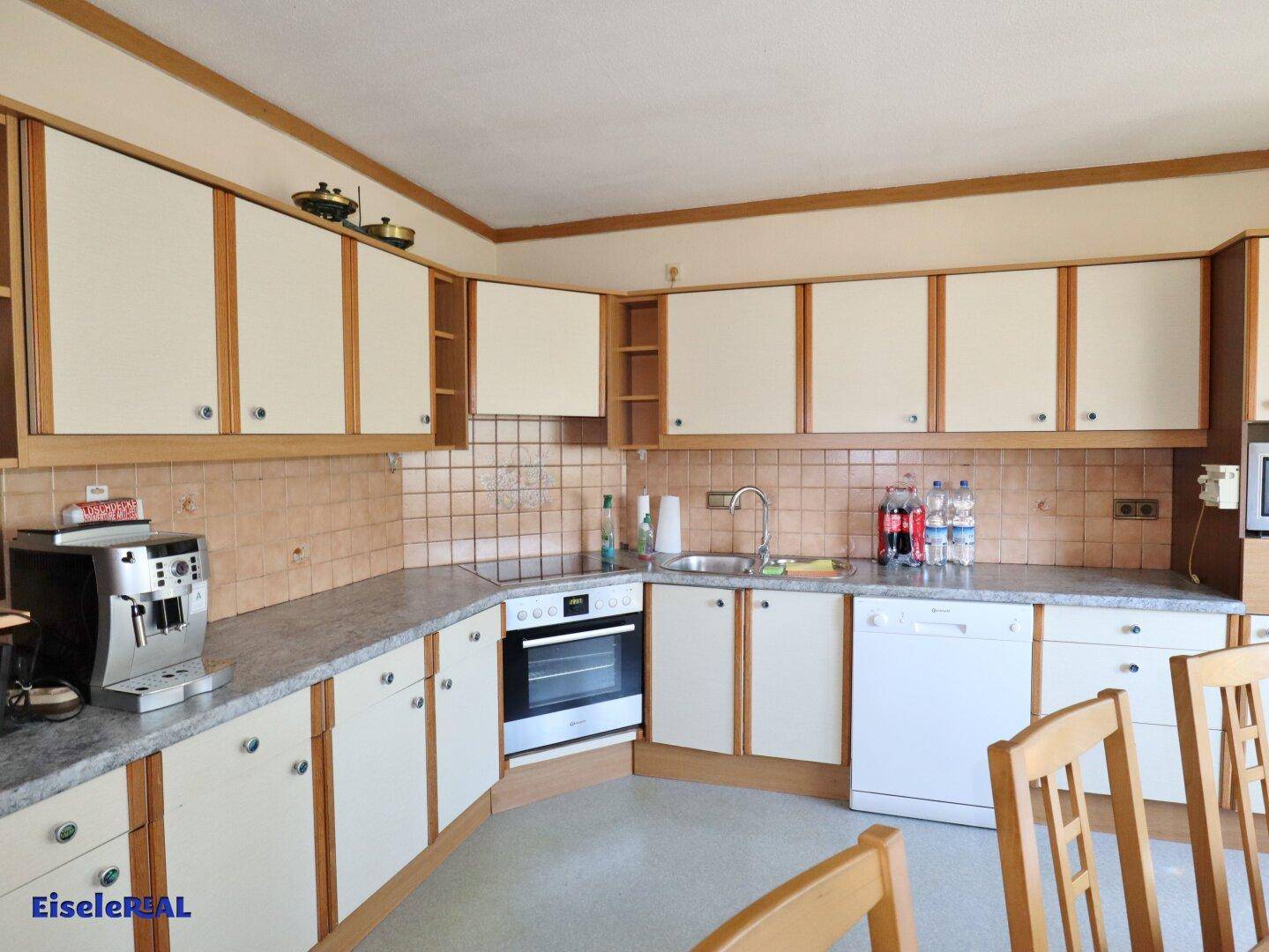 Funktionale Küche mit hellen Holzschränken, Fliesenrückwand und integrierten Geräten.