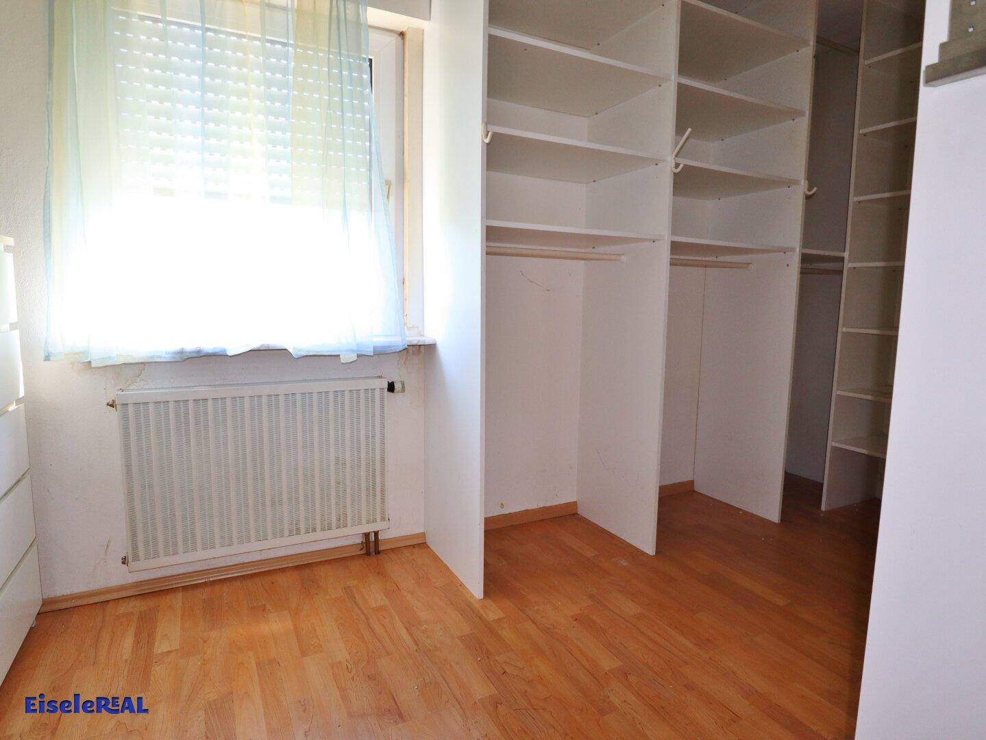 Praktischer begehbarer Kleiderschrank mit vielen offenen Regalen und hellem Holzboden.