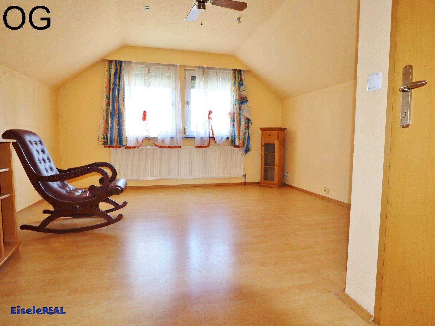 Helles Schlafzimmer im Obergeschoss mit hellem Laminatboden und einem Schaukelstuhl.