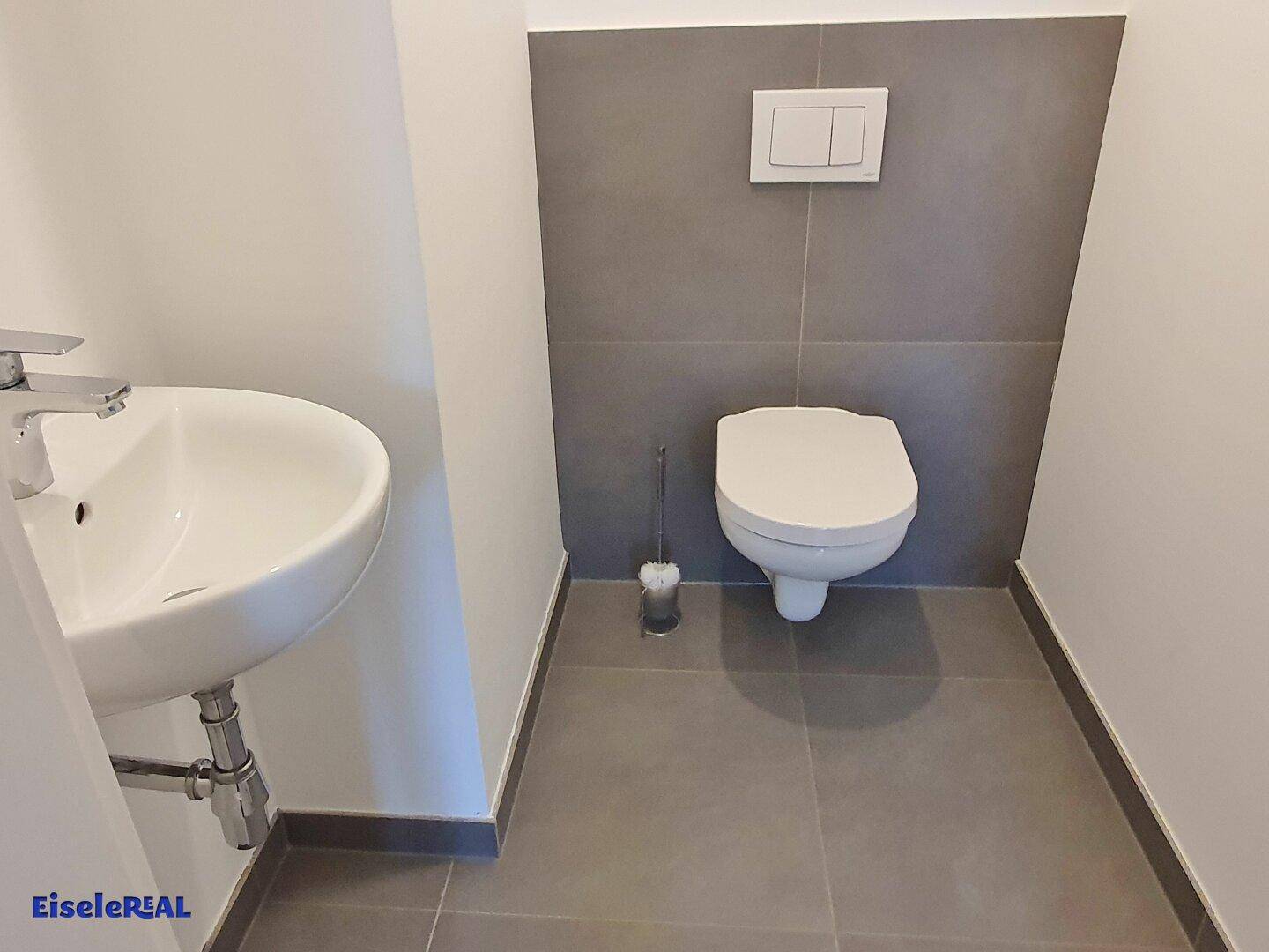 Modernes Gäste-WC mit wandhängender Toilette und kleinem Waschbecken.